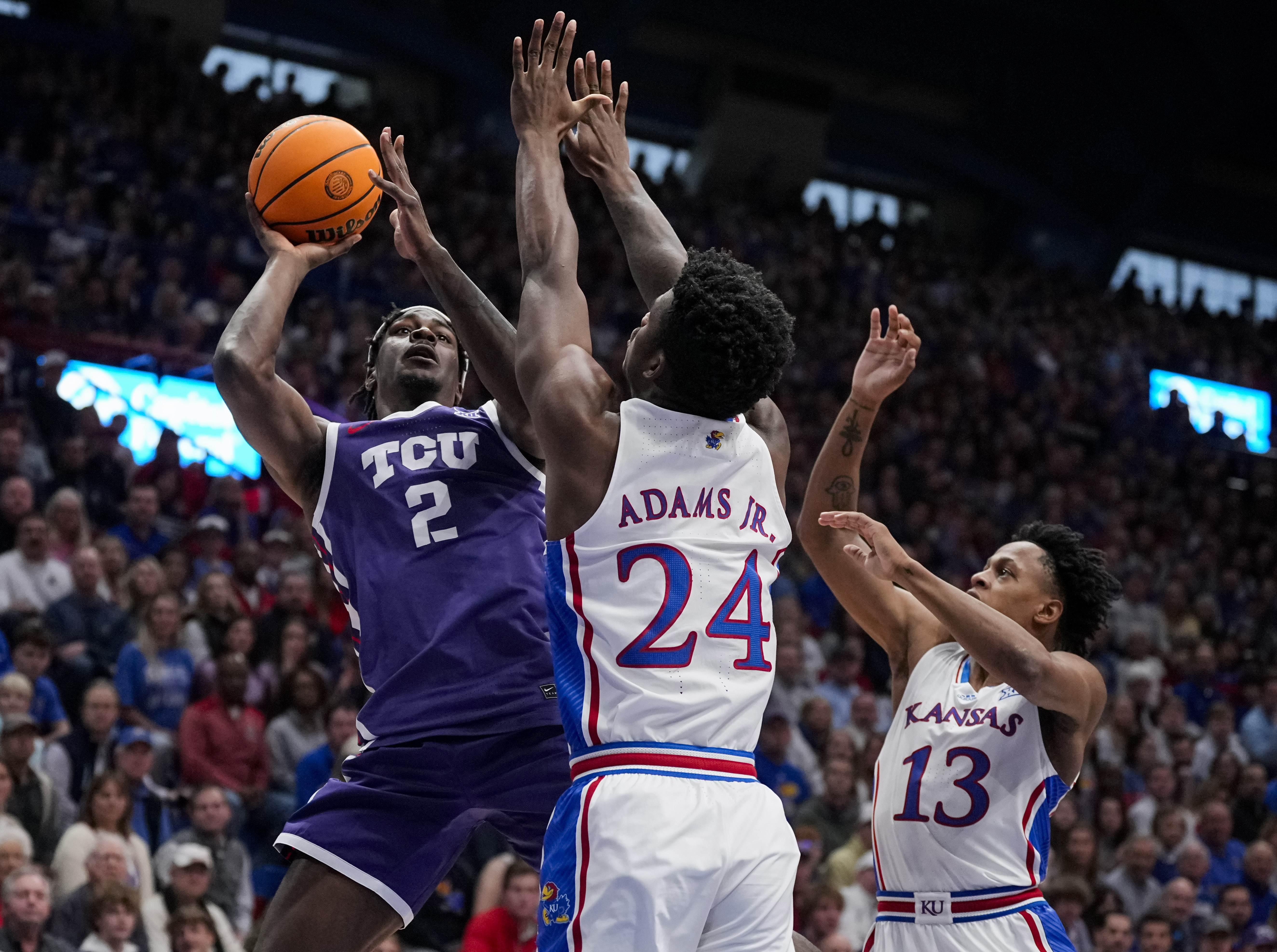 Jan 6, 2024; Lawrence, Kansas, USA; TCU Horned Frogs forward Emanuel Miller (2) shoots against Kansas Jayhawks forward K.J. Adams Jr. (24) and guard Elmarko Jackson (13) during the first half at Allen Fieldhouse. Mandatory Credit: Jay Biggerstaff-USA TODAY Sports